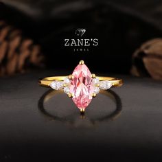 a pink diamond ring sitting on top of a black surface with the name zane's jewel