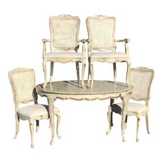 a set of six chairs and a table with one chair on the other side, all in white