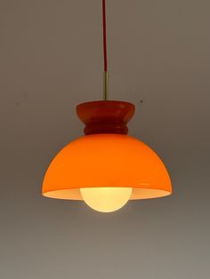 an orange light hanging from a ceiling with a red cord attached to the end of it