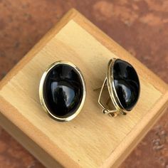 Estate/ Vintage polished 14KT yellow gold omega back earrings with oval, bezel-set, genuine, black onyx. Wear them by themselves or interchange earring charms in them! Charms shown are sold separately. Entire earring measures: 20mm x 15mm Weight: 5.3 grams Omega back closure Stamped 14K Excellent estate condition Classic Oval Clip-on Earrings With Polished Finish, Formal Clip-on Earrings With Oval Cabochon, Classic Oval Clip-on Earrings, Modern Oval Cabochon Earrings, Classic Oval Clip-on Earrings For Formal Occasions, Elegant Oval Clip-on Jewelry, Classic Oval Cabochon Gemstone Earrings, Elegant Onyx Oval Cabochon Jewelry, Classic Oval Clip-on Jewelry