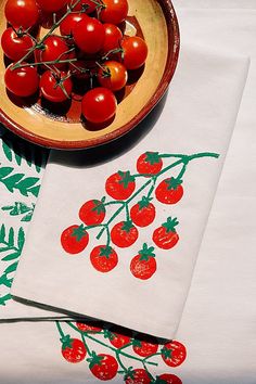 tomatoes are on the table next to some napkins and a bowl of cherries