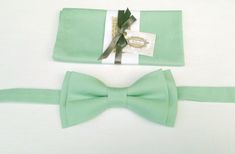 a green bow tie sitting on top of a white table next to a piece of paper