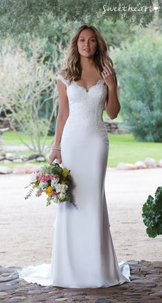 a woman in a white wedding dress holding a bouquet and looking at the camera with her hand on her hip