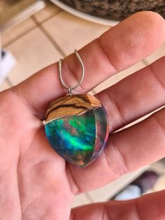 Unique litlle resin dark opal pendant, made of olive wood, resin, and synthetic opal in red/blue/orange color,  Made from the ancient olive wood tree (more than 100 years old). Dried wood. Made in the home craft. Shaped perfectly. Each piece is unique. Comes in a decorative box, ready as a gift. The creation of unique personalized jewelry is the mission. The quality of the performance of each piece of jewelry and the same love and dedication to each of them is the premise. Behind the name "Jewel Multicolor Teardrop Necklace For Gift, Green Inlay Necklace As Gift, Handmade Opal Necklaces As Gift, Handmade Opal Necklaces For Gift, Artisan Necklace With Natural Inclusions As A Gift, Iridescent Resin Jewelry For Gifts, Artisan Opal Necklaces As Gifts, Iridescent Oval Pendant Necklace Gift, Artisan Opal Necklaces For Gifts