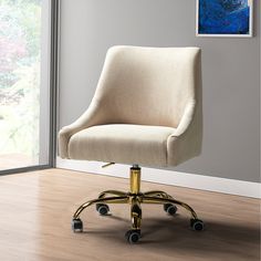 an office chair with wheels and a painting on the wall behind it, in front of a window