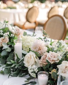 the table is set with candles, flowers and greenery for an elegant wedding reception