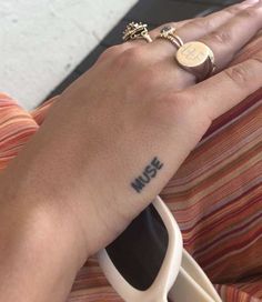 a person with a ring on their left hand and the word music tattooed on her right wrist