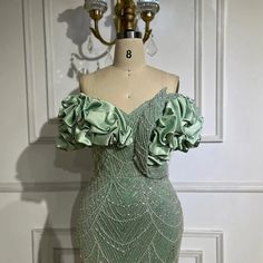 a green dress with ruffles on the shoulders and shoulder, sitting on a mannequin