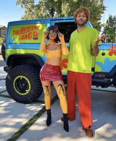 a man and woman dressed up in costumes standing next to a truck with the words mystery gang on it