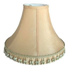 a beige lamp shade with tassels and beads on the bottom, sitting on a white background