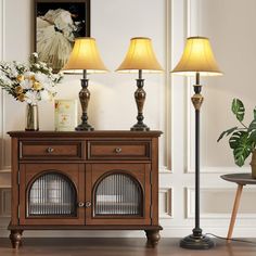 a wooden cabinet with three lamps on top of it