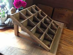 a wooden box with compartments on it sitting on a table next to a potted plant