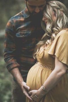 a pregnant couple cuddles in the woods while holding each other's belly