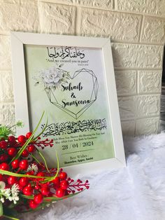 a white frame sitting on top of a bed next to red berries and greenery