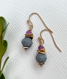 "The dainty size of these earrings makes them perfect for those who appreciate delicate and intricate jewelry. The carefully chosen beads, with their rich purple and delicate blue hues, lend a sense of mystique and depth to the earrings, making them an ideal choice for both casual and special occasions. Drop length: 1.5\" Width: .33\" Each Garnish and Grace piece is made in our home studio in the Finger Lakes region of New York State where we draw our inspiration from the surrounding countryside Single Purple Drop Earring, Purple Single Drop Earring, Purple Drop Earrings With Dangling Beads, Dainty Earrings With Dangling Round Beads, Purple Dainty Earrings With Ear Wire, Dainty Purple Earrings With Ear Wire, Beaded Amethyst Earrings Gift, Beaded Amethyst Earrings For A Gift, Amethyst Beaded Earrings As Gift