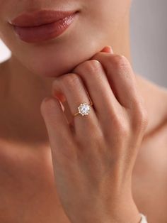 a woman wearing a diamond ring with her hand on her chin, looking at the camera