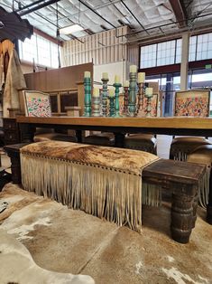 an old table with fringes on it in a room filled with chairs and other items