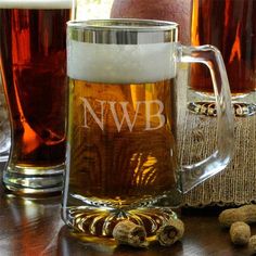 two mugs filled with beer sitting on top of a table next to some nuts