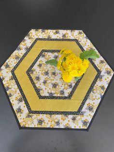 a yellow and black table with flowers on it, sitting next to a gray background