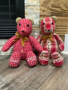 two teddy bears sitting next to each other on a wooden floor in front of a fireplace