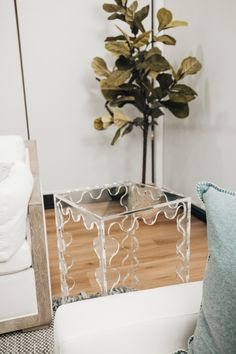 a white chair sitting next to a glass table on top of a hard wood floor