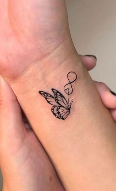 two people holding each other's hands with tattoos on their wrist and one has a butterfly tattoo on it