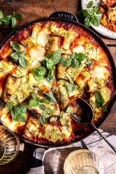 a pizza sitting on top of a pan covered in cheese and spinach next to other dishes