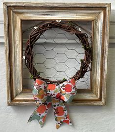 a wreath hanging on the side of a wall next to a chicken wire frame with a bow