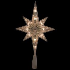 a lighted christmas star hanging from the ceiling in front of a black background with white lights