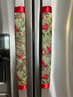 two red birds are sitting on the handles of a stainless steel refrigerator with matching handles