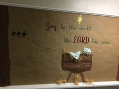 a nativity scene is displayed in front of a bulletin board that says, joy to the world the lord has come