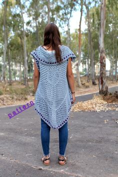 a woman standing in the middle of a road wearing a blue crochet top