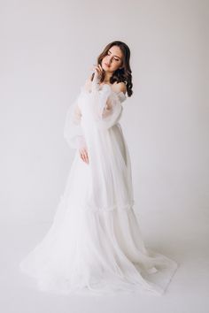 a woman in a white dress posing for the camera with her hands on her hips