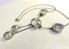 Originally $650.00. Circa 1930. Gorgeous Art Deco Era necklace featuring clear faceted crystal stones of oval and round shapes bezel set in Sterling Silver. This elegant necklace is a beautiful and versatile piece that could be worn for day or evening. It would be a wonderful piece to layer with other Deco crystal and paste pieces. Measurements: Central oval stone: Approx. 20mm x 15mm Oval stones on each side of the central Stone: Approx. 12mm x 8mm 2 round dangling round stones: Approx. 11mm in Vintage Silver Necklace With Single Cut Diamonds, Vintage Formal Necklace With Single Cut Diamonds, Art Deco Silver Necklace With Single Cut Diamonds, Vintage Necklace With Single Cut Diamonds For Formal Occasions, Vintage Single Cut Diamond Necklace For Formal Occasions, Vintage Single Cut Diamond Necklaces For Formal Occasions, Vintage Silver Necklaces With Single Cut Diamonds, Formal Art Deco Necklaces With Single Cut Diamonds, Vintage Oval Necklace With Rose Cut Diamonds