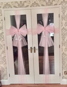 two white double doors with pink bows and numbers on the front door for wedding guests