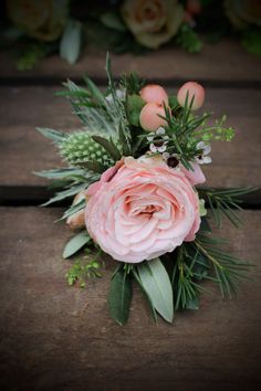 a bouquet of pink flowers sitting on top of a wooden table next to greenery