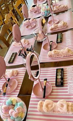 the table is set up with pink and white striped tables cloths, candy bar utensils, and candies