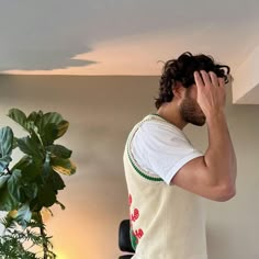 a man standing in front of a plant holding his head