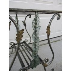 an iron table with glass leaves on it's top and bottom, sitting in front of a garage door