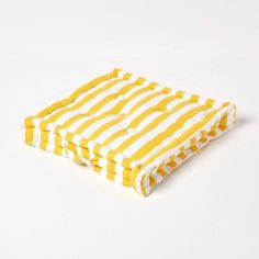 a yellow and white striped pillow on a white surface with no one in the photo