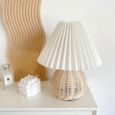 a white lamp sitting on top of a table next to a vase and candle holder