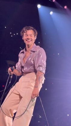 a man standing on top of a stage with a microphone in his hand and smiling