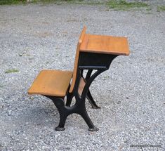 an old school desk and chair sitting on gravel