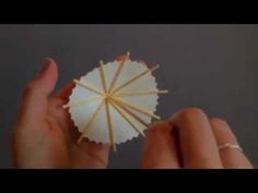 a person holding an umbrella made out of toothpicks in their left hand,