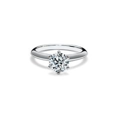 a white gold engagement ring with a round brilliant cut diamond in the center, on a plain surface