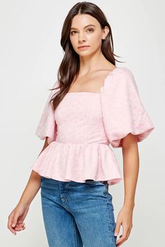 a woman is wearing a pink top with ruffles on the sleeves and shoulders