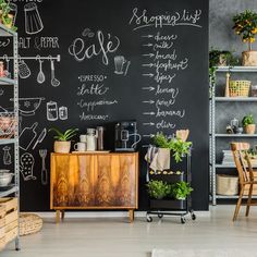 a chalkboard wall in the corner of a room with wooden furniture and potted plants