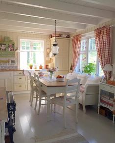 a dining room table and chairs in front of a window with red checkered curtains