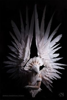 a woman with white wings on her face and body, in front of a black background