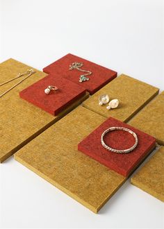 three pieces of jewelry are on display in red and gold cases, with matching earrings